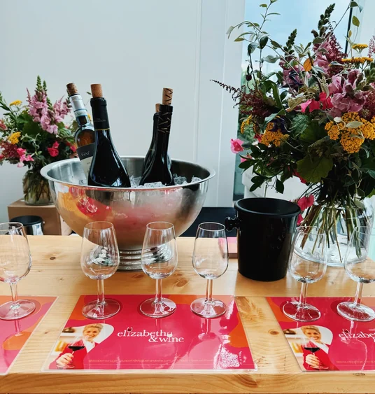 Wine bottles chilling in an ice bowl beside tasting glasses, flowers and Elizabeth & Wine mats