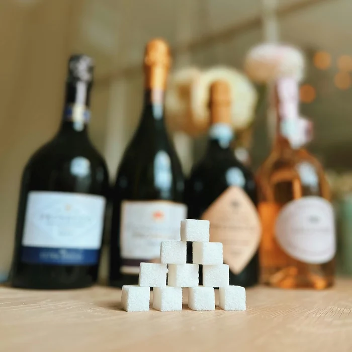 Sugar cubes stacked in front of blurred champagne and wine bottles