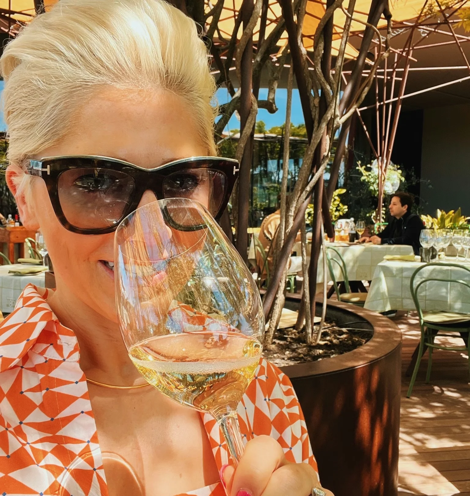 Elizabeth Hawthornthwaite raises a glass of white wine at an outdoor restaurant in Tuscany.