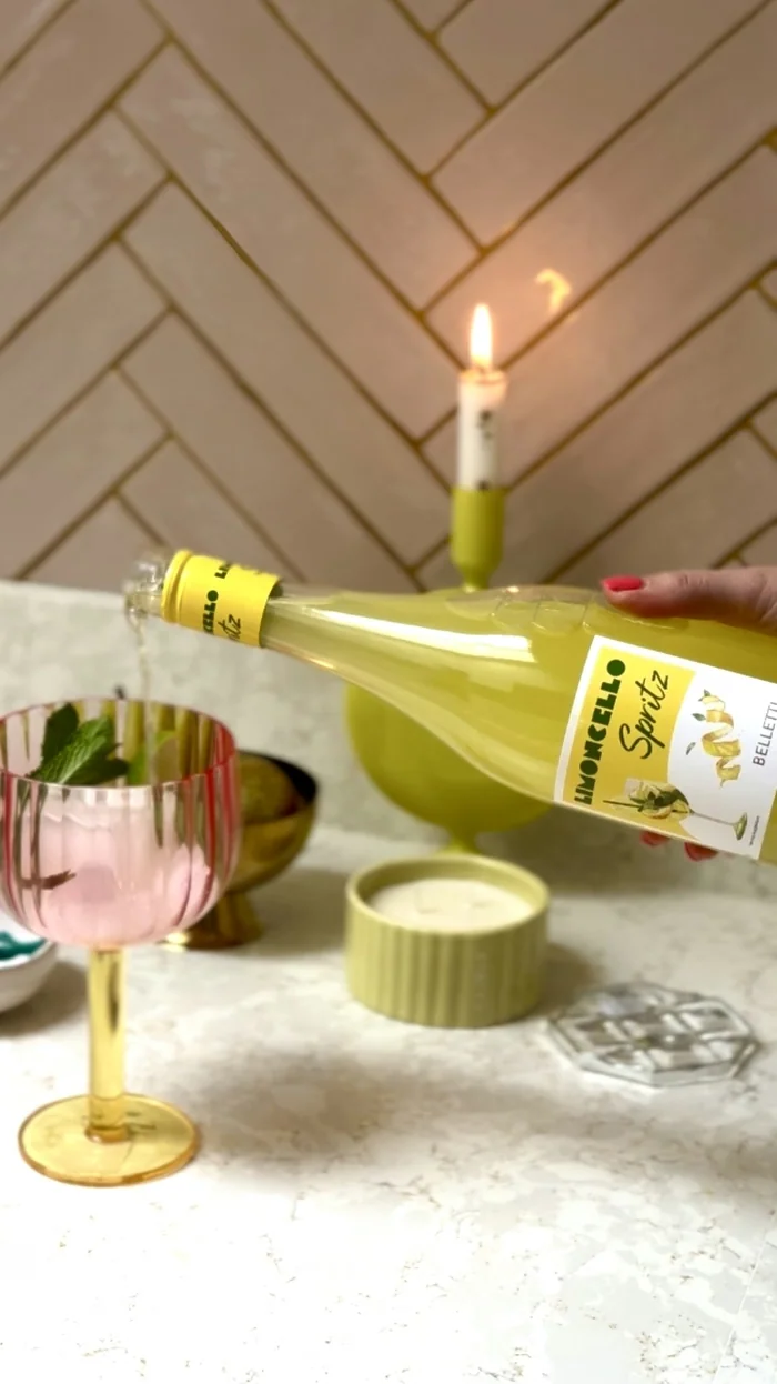 Pouring sparkling wine into pink glass beside lit candle