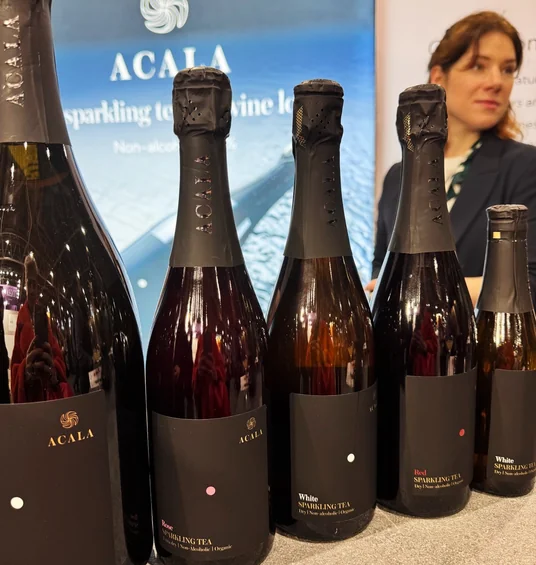 Acala sparkling tea bottles displayed at Wine Paris, with a woman and Acala stand behind them