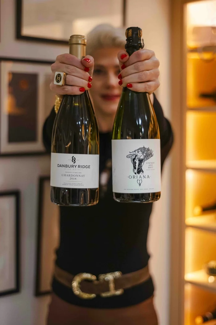 Person holding two sparkling wine bottles indoors