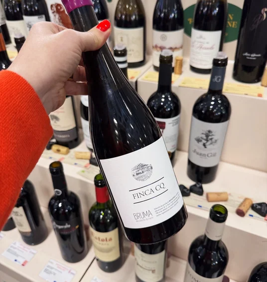 A hand holds a bottle of Finca CQ Bruma wine at a Wine Paris 2025 exhibition stand.