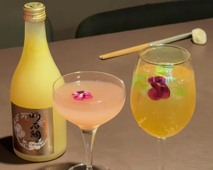 Bottle and two floral cocktails on table