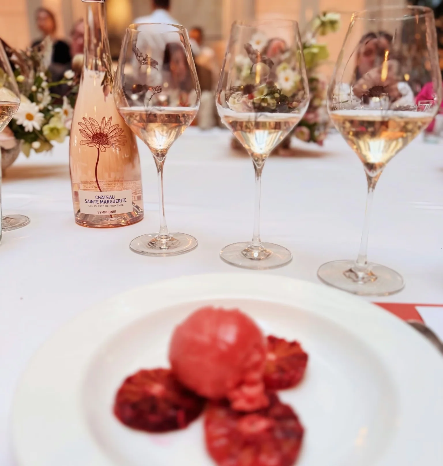 Three glasses of rosé and a Château Sainte Marguerite bottle beside a plate of tomato sorbet