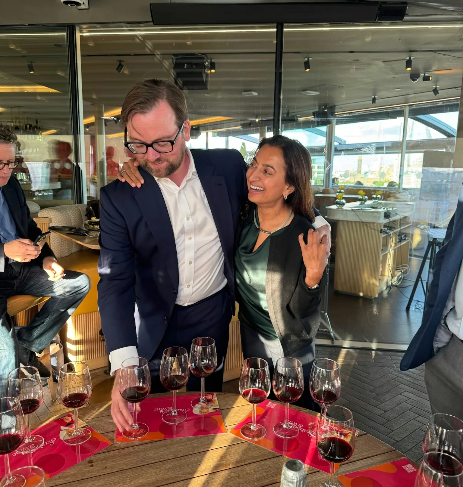 Guests gather around a table of red wine glasses during a blind tasting at a bright restaurant venue.