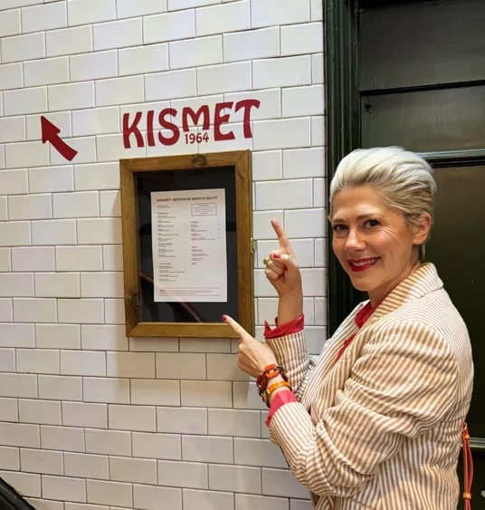 Woman pointing to the Kismet restaurant sign and menu