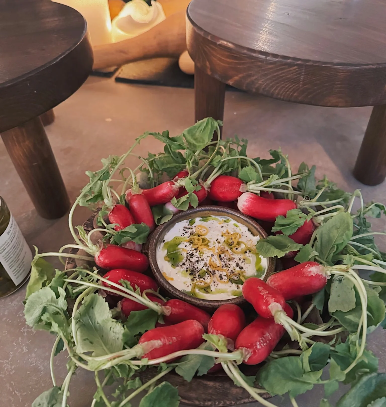 Radishes and herbs arranged around a bowl of dip on a rustic table