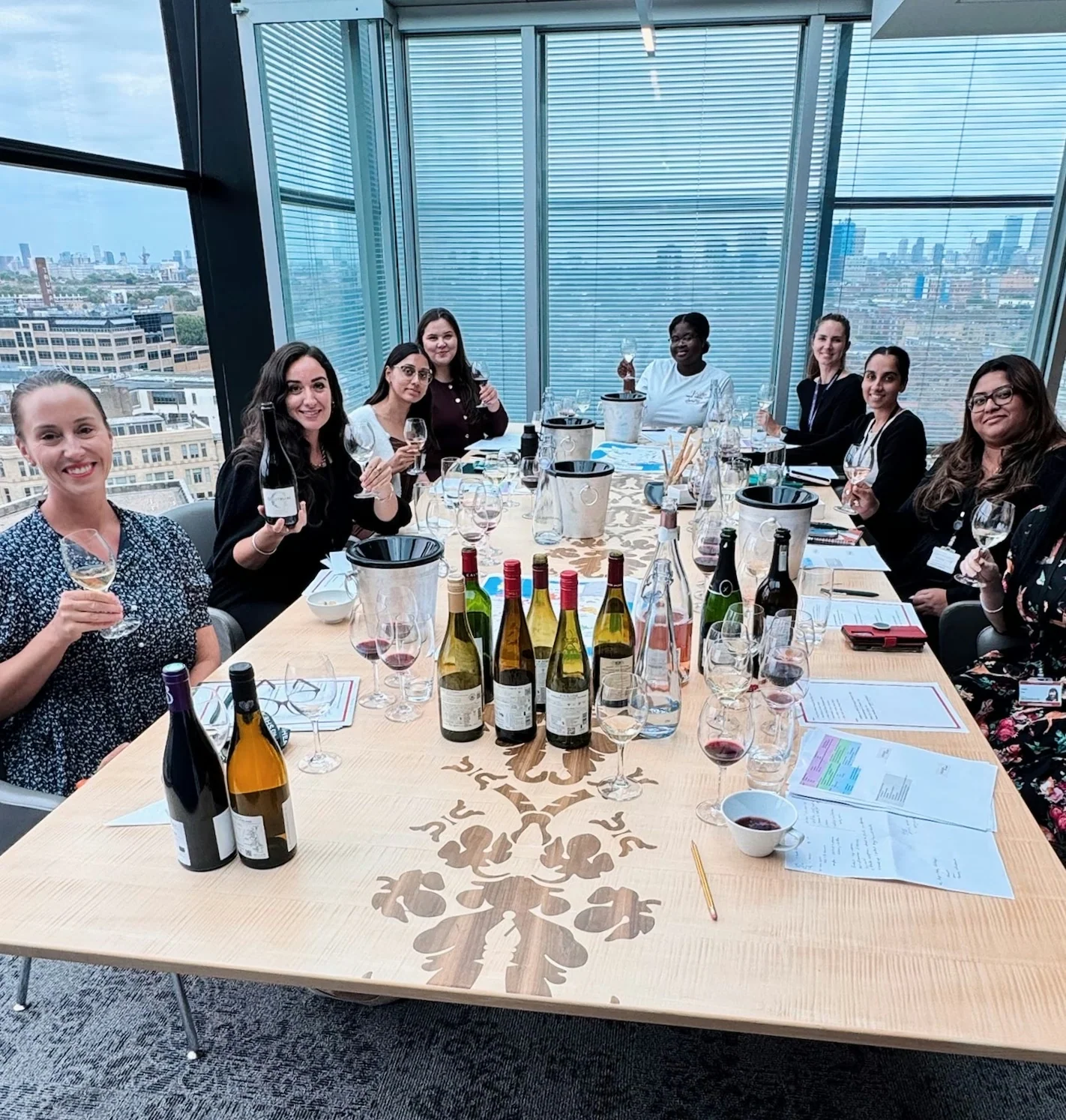 Group tasting wine around a conference table with London visible through the windows