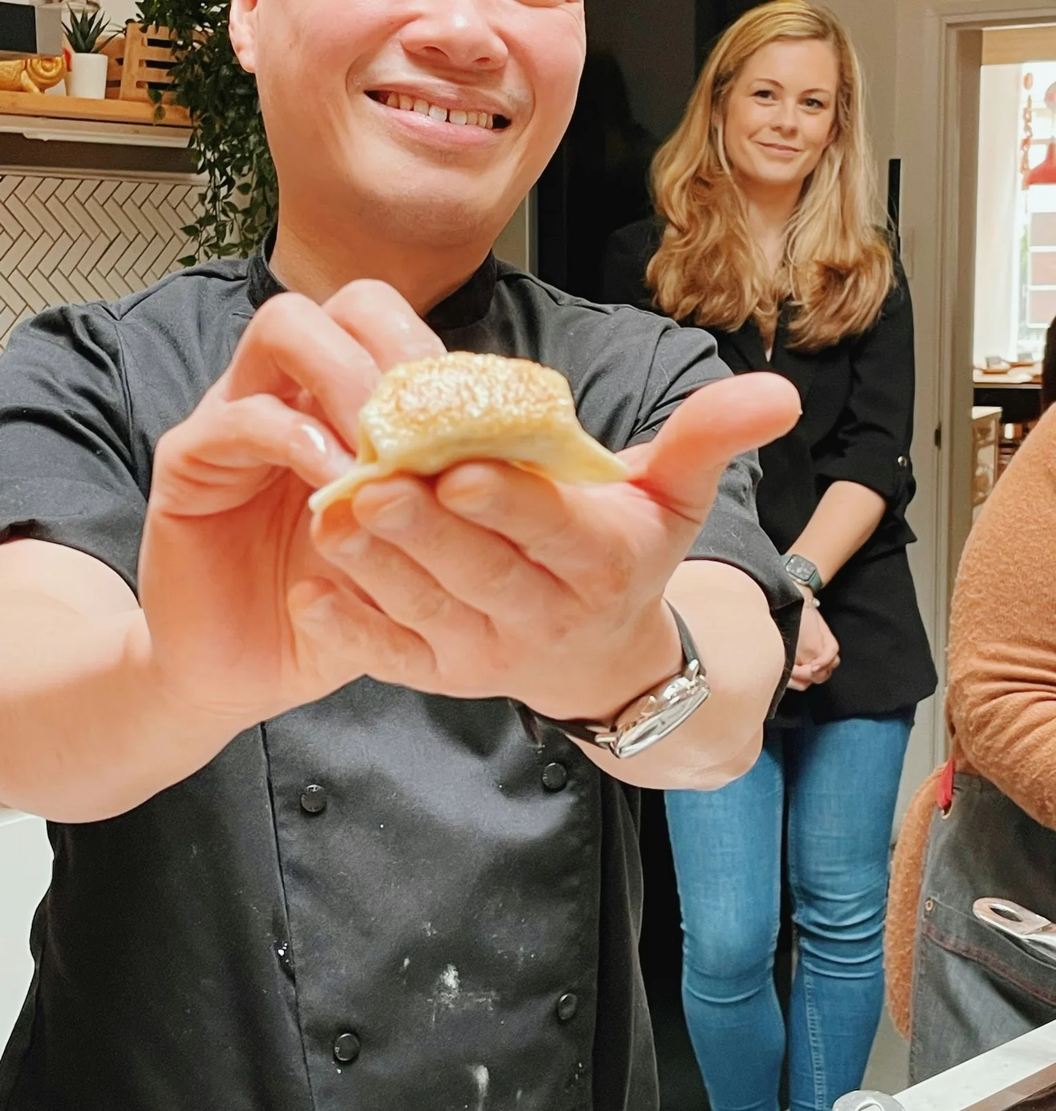 Chef presenting a small pastry to the camera during an indoor tasting event