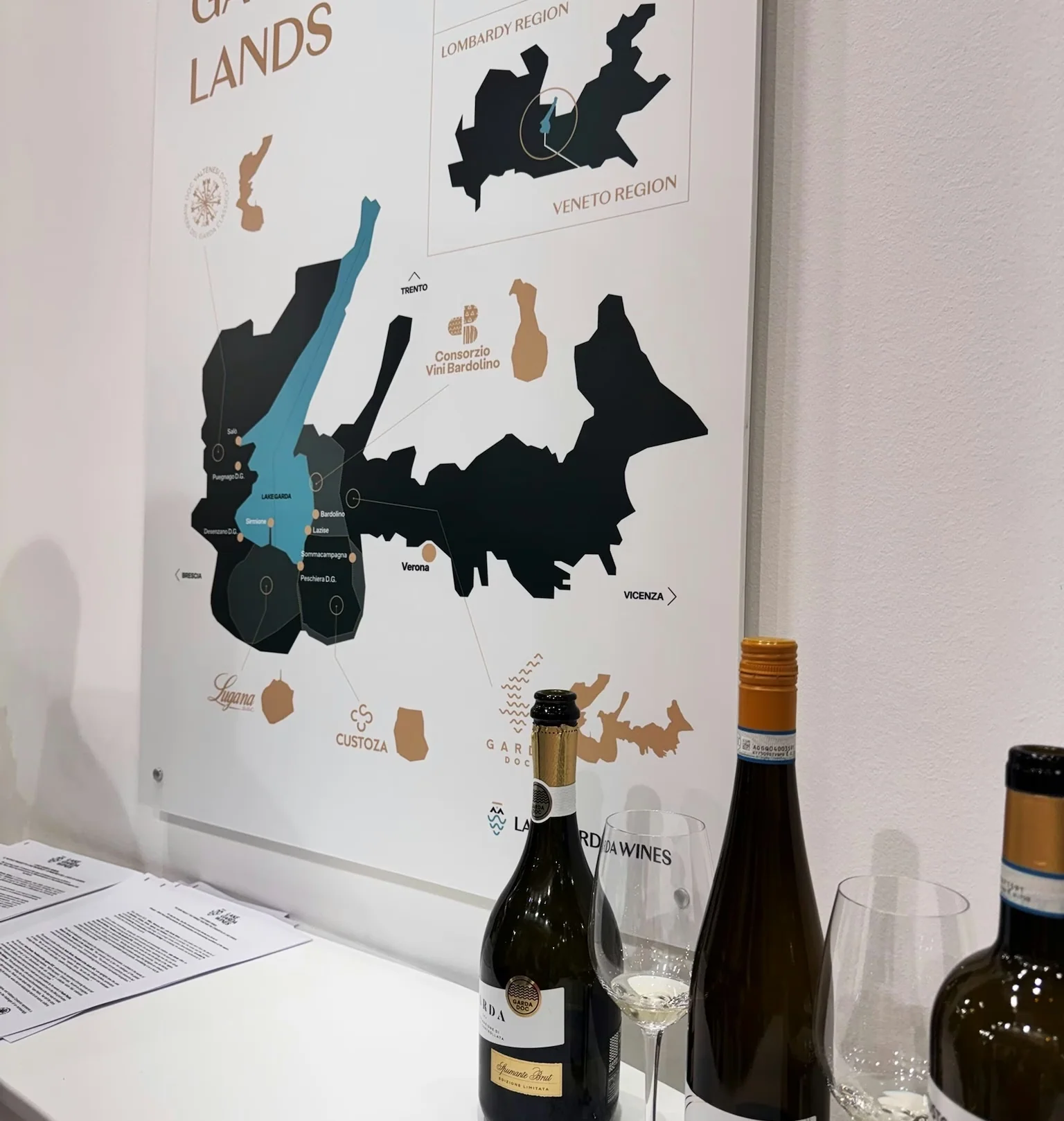 Wine bottles and tasting glasses displayed beneath a Lake Garda lands map at Wine Paris