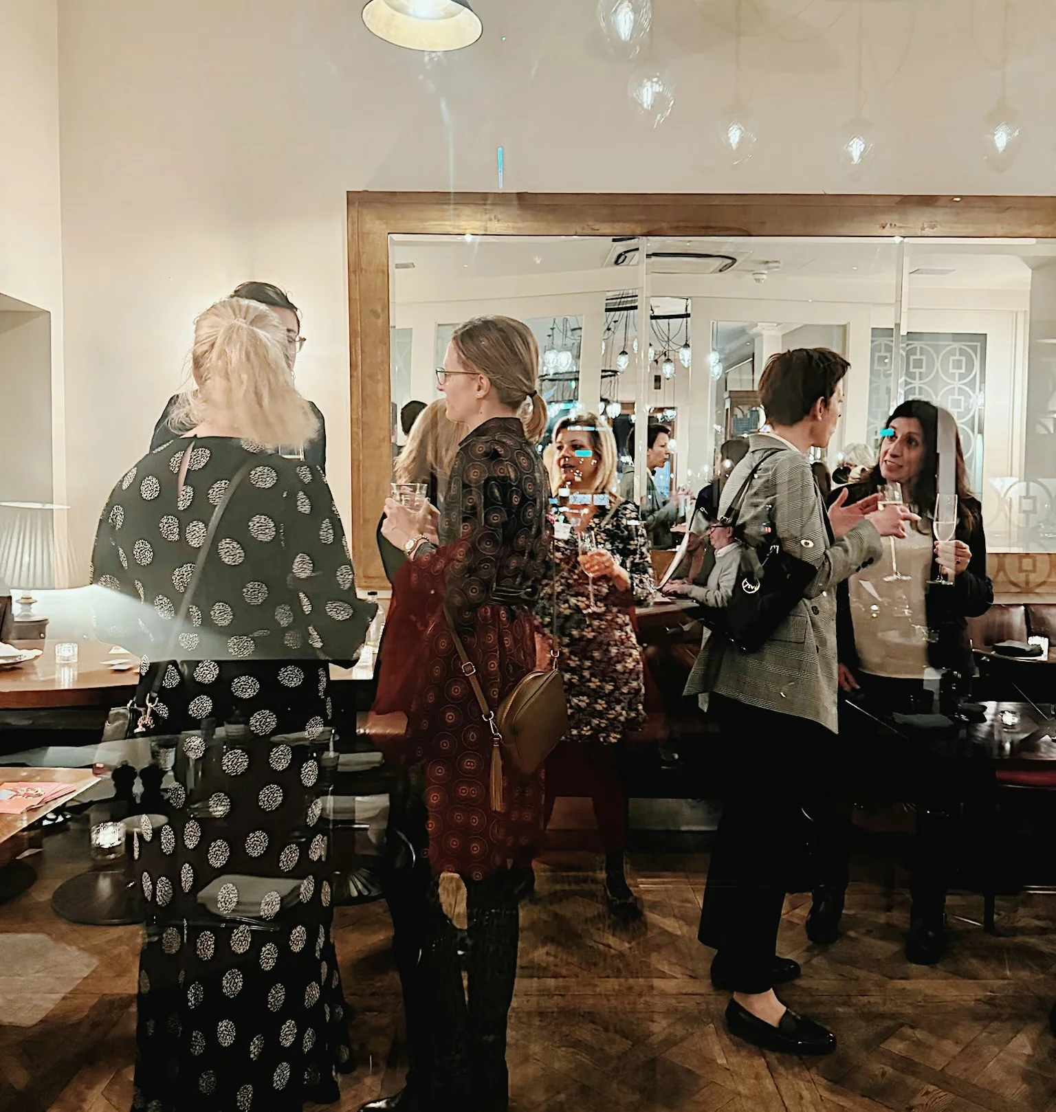 Guests mingle with wine glasses in an elegant restaurant dining room