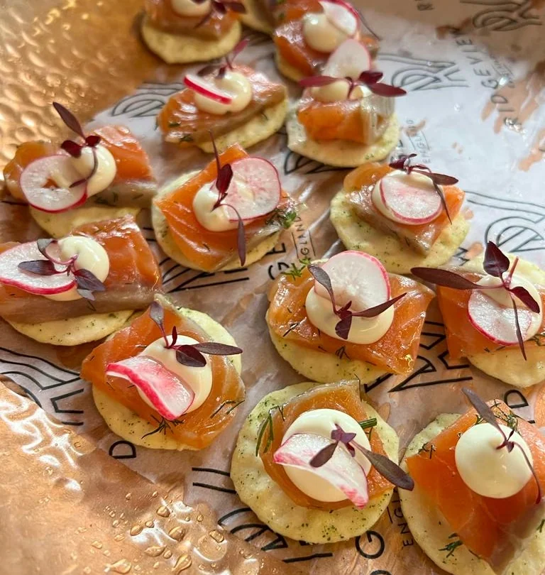 Canapés topped with smoked salmon, radish, cream and microgreens on branded Ridgeview paper