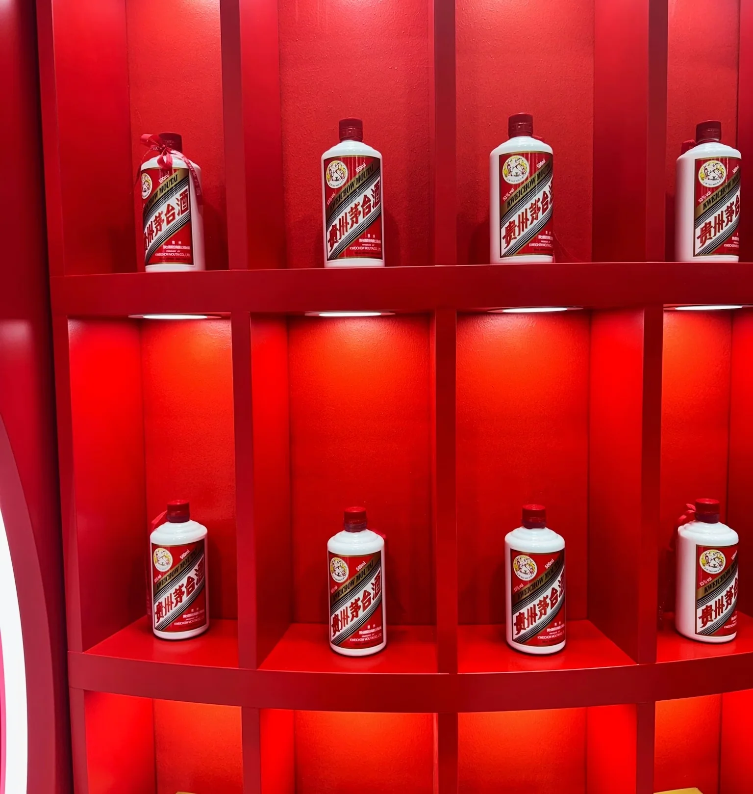 Red display shelving holds rows of white Moutai bottles and red-and-gold Moutai boxes