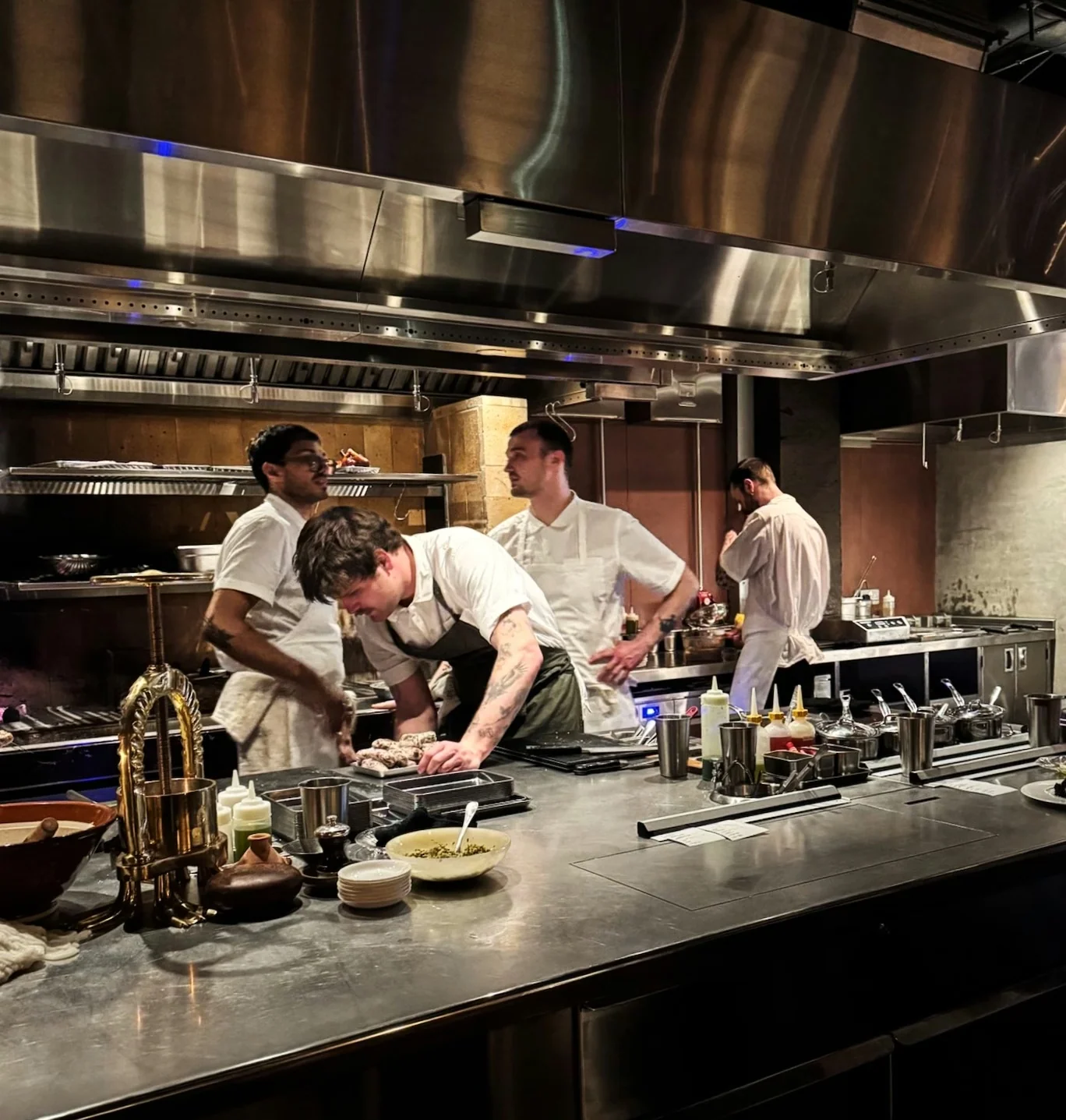 Chefs preparing food at a stainless steel restaurant kitchen counter