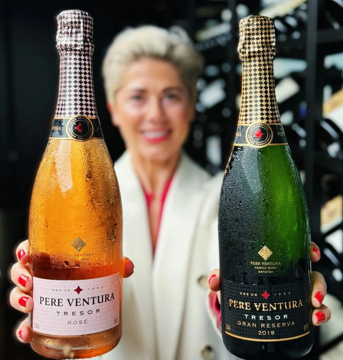 Two chilled Pere Ventura Cava bottles held in front of a blurred person