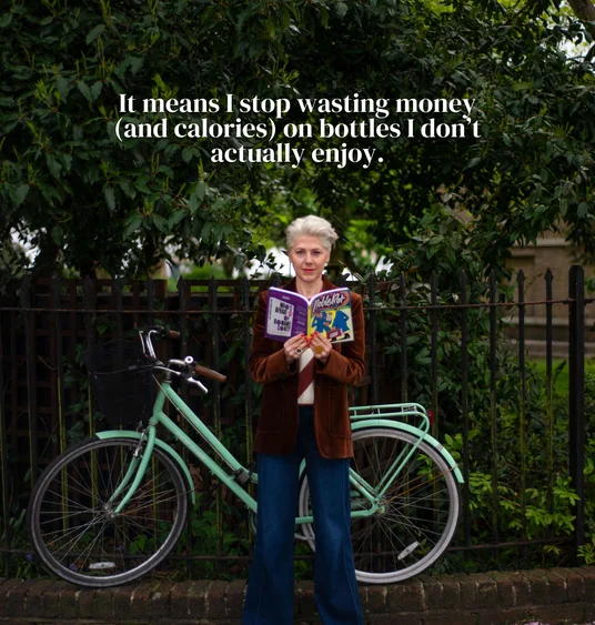 Person holding an open comic book beside a mint-green bicycle under leafy trees