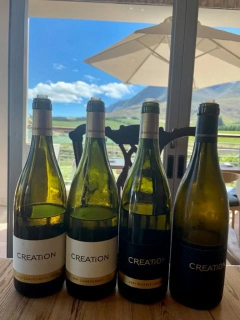 Four Creation wine bottles on a table with mountain view
