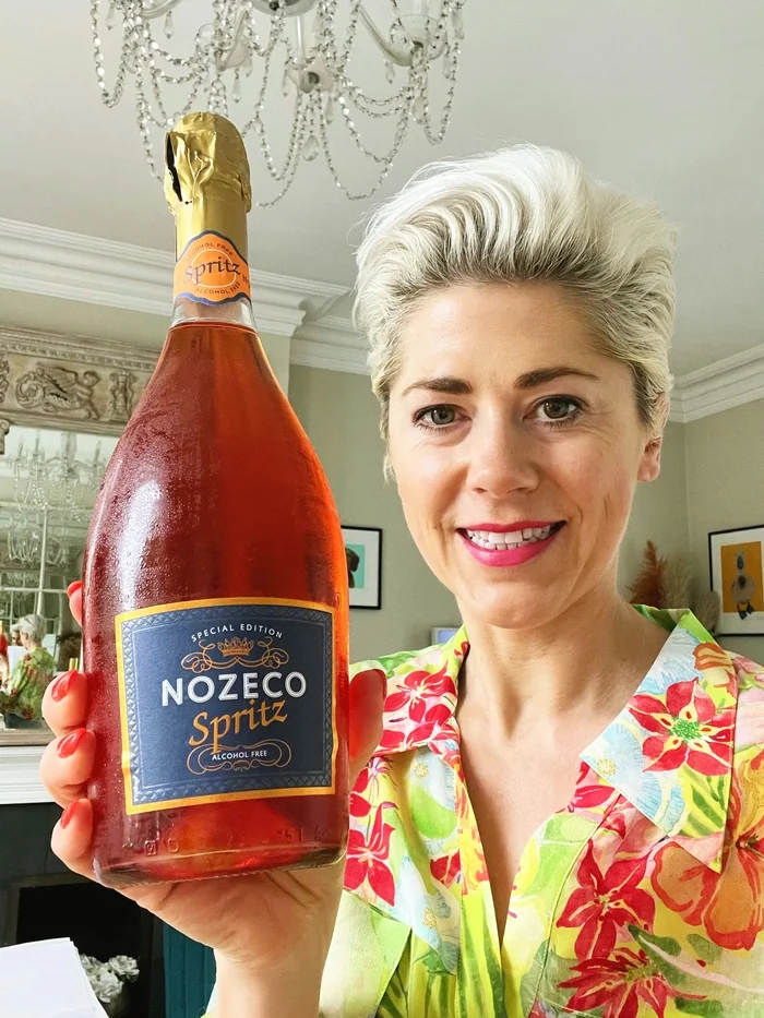 Woman holding Nozeco Spritz bottle in elegant room