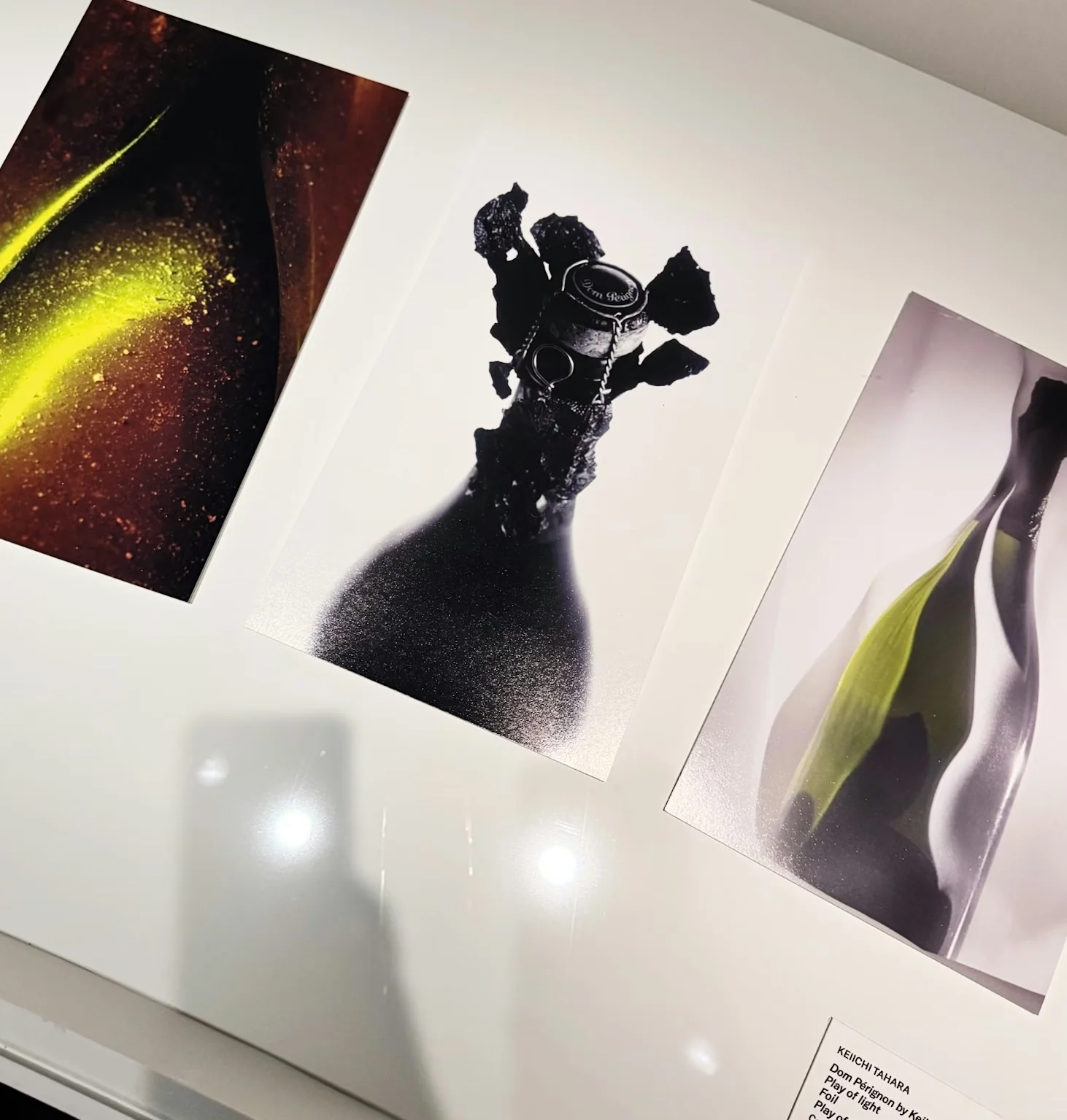 Dom Pérignon bottle artwork displayed with abstract prints in a gallery case