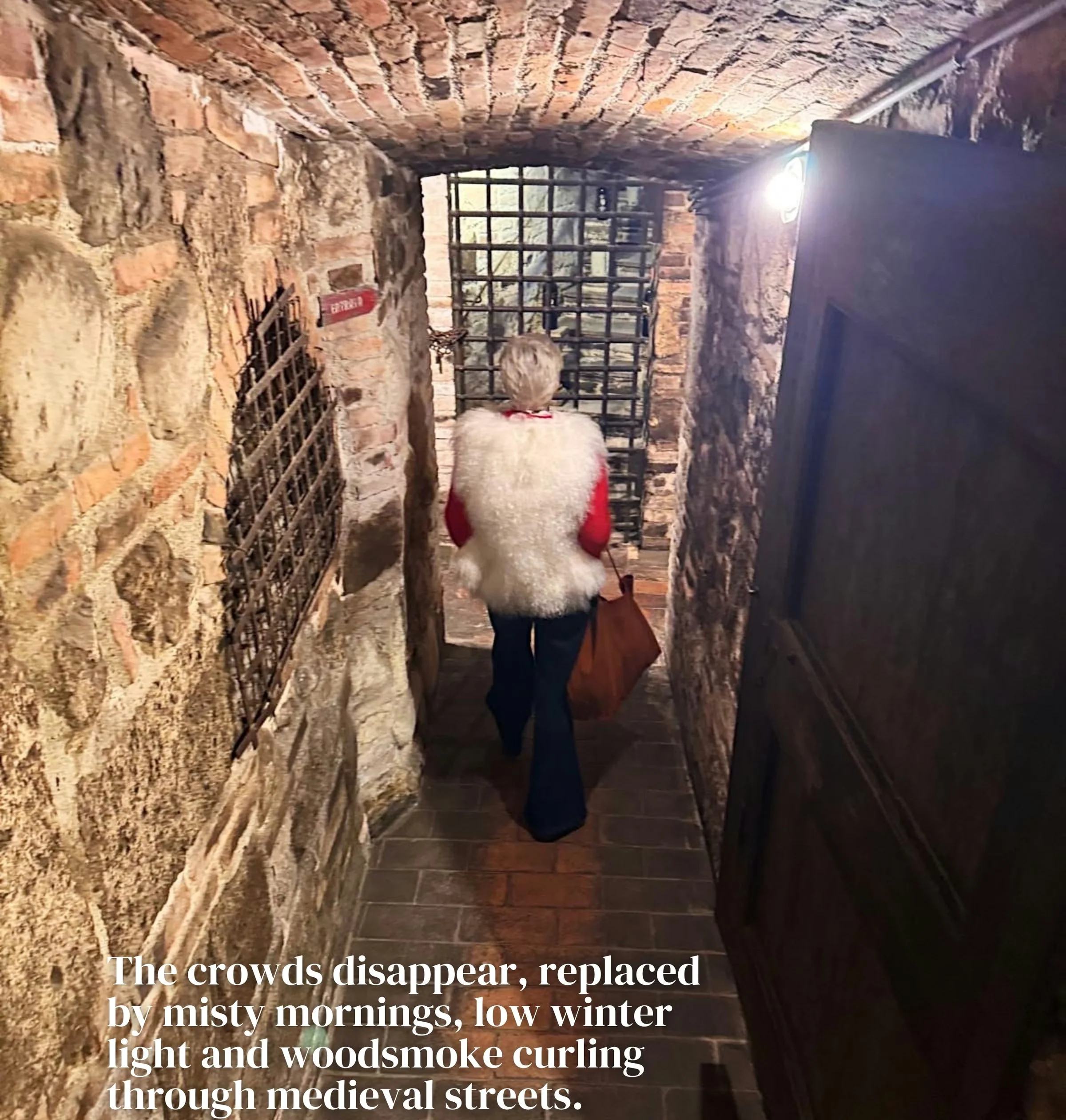 Visitor walking through a vaulted brick wine cellar in Montalcino