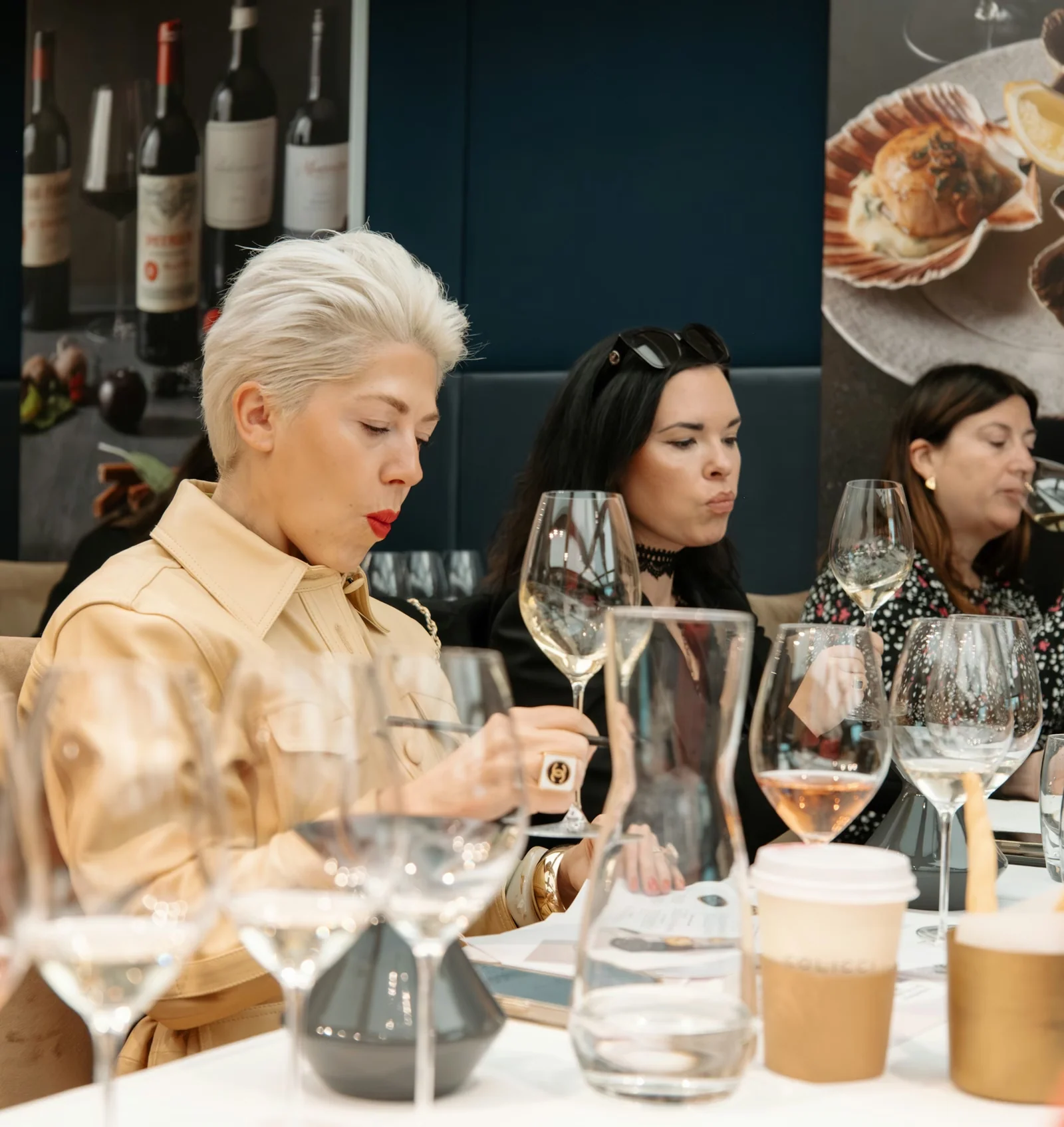 Guests taste wine around a table filled with glasses in a stylish restaurant
