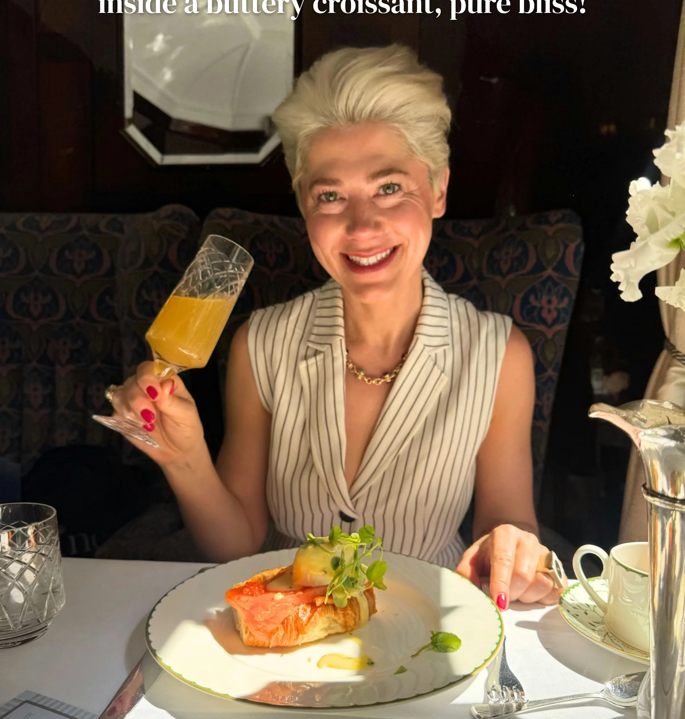 Diner raising a glass beside a plated smoked fish dish aboard a luxury train