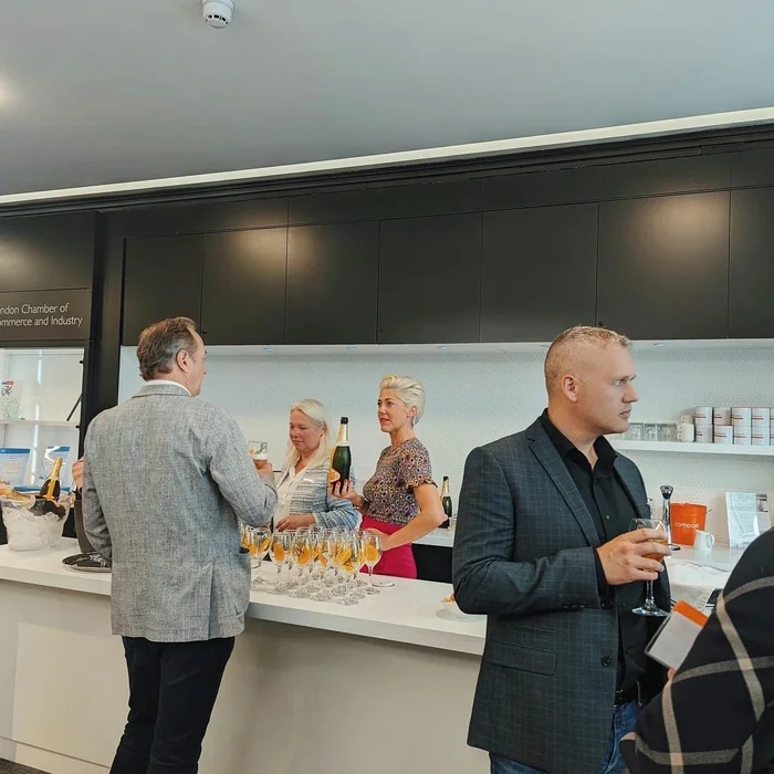 Guests sample wine at a tasting bar, with bottles and glasses displayed in a London Chamber of Commerce venue.