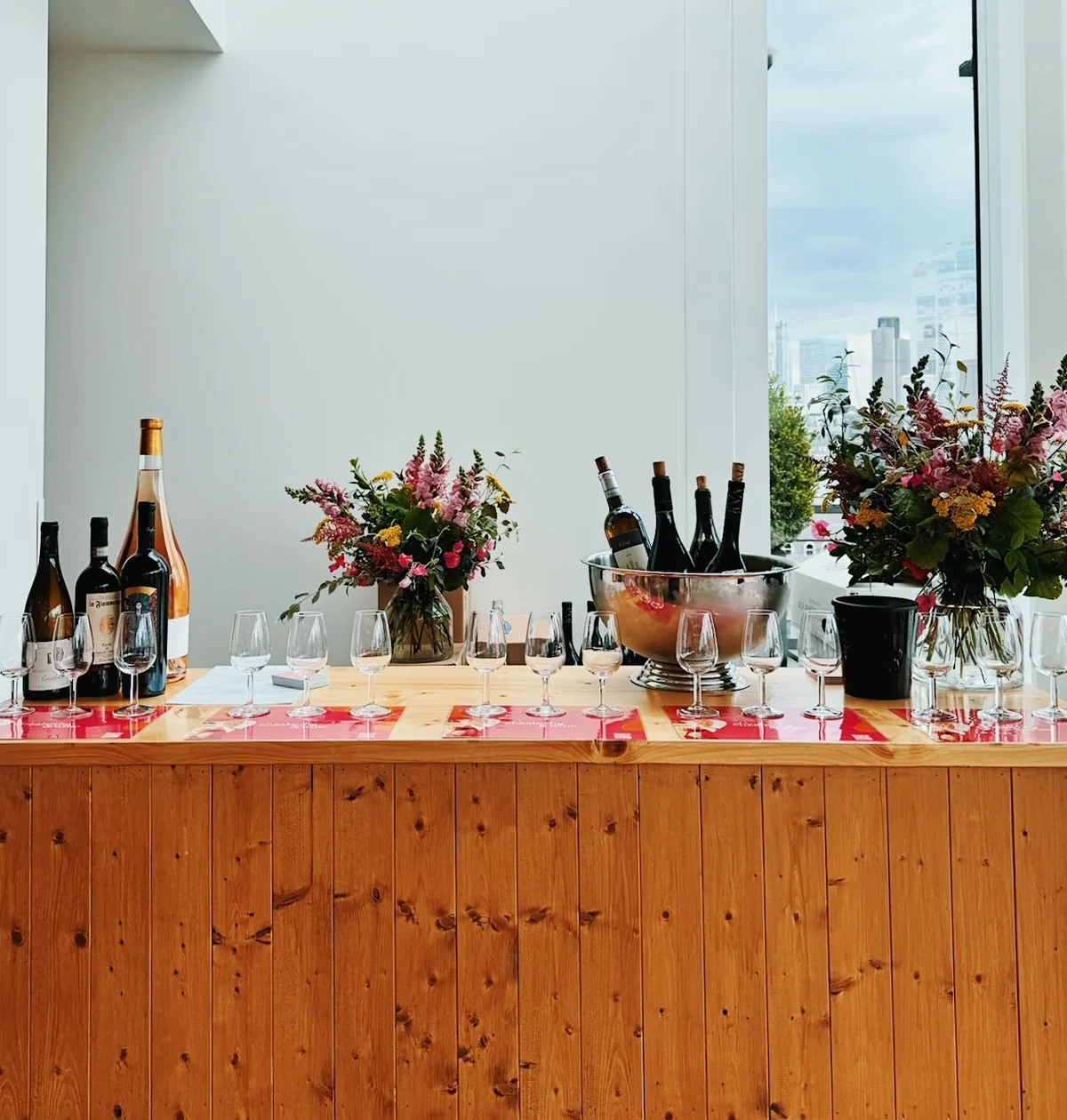 Wine tasting table with glasses, bottles, flowers and a city view
