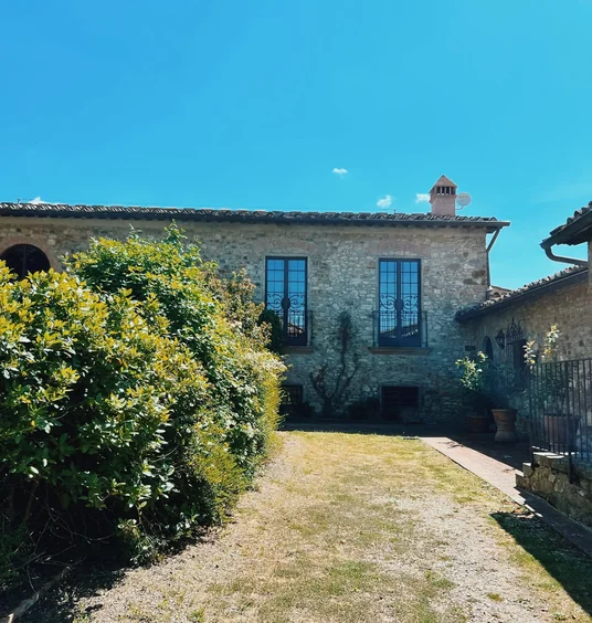 Stone courtyard at Fontodi Winery in Tuscany, with a hedge, dry lawn and blue sky