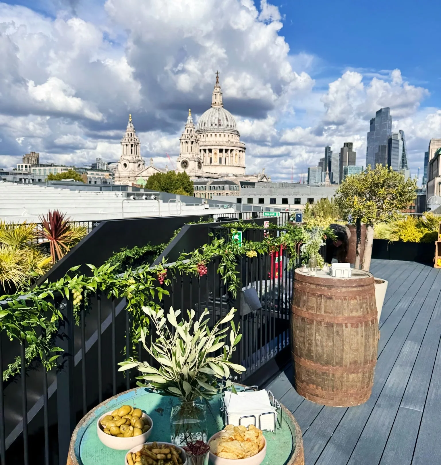 Rooftop drinks table with snacks and greenery overlooking St Paul's Cathedral and the City of London