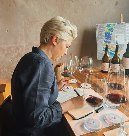Wine professional tasting red wine beside several glasses and bottles