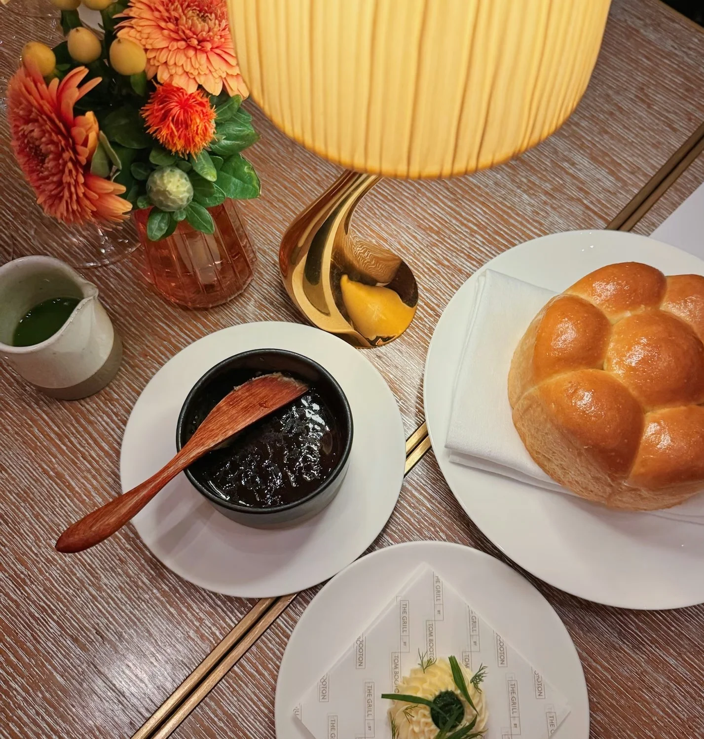 Restaurant table with bread, jam, flowers, dessert and a glowing table lamp