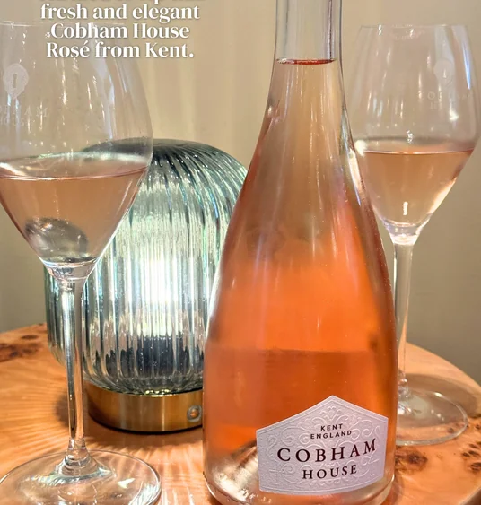 Cobham House rosé bottle with two filled wine glasses on a wooden table