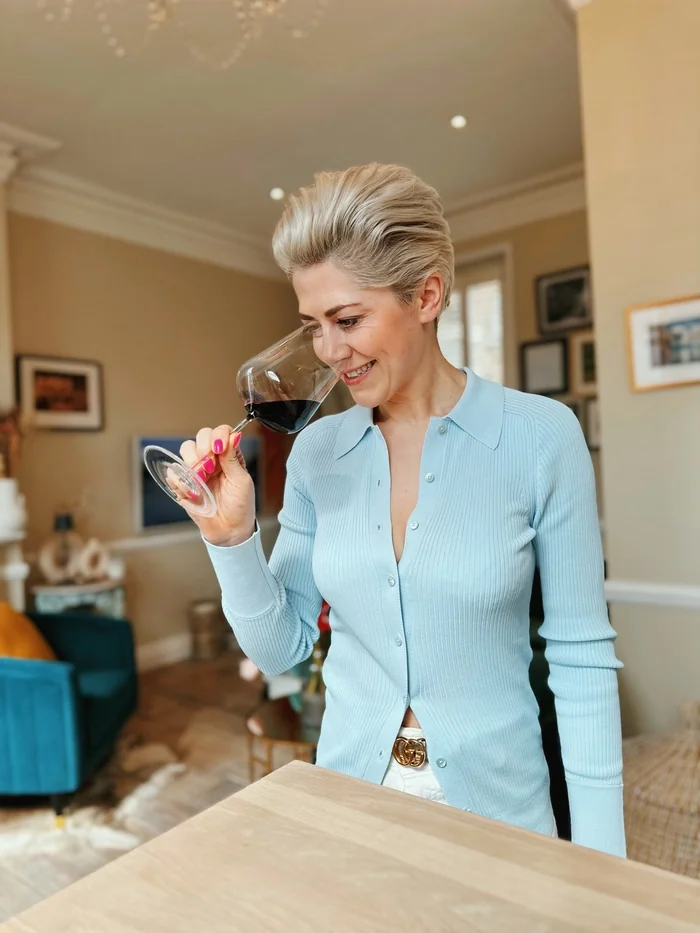Woman smelling red wine in a glass at home