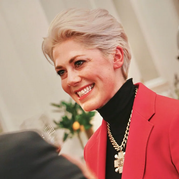 Elizabeth Hawthornthwaite smiling at an event while wearing a red blazer and black top