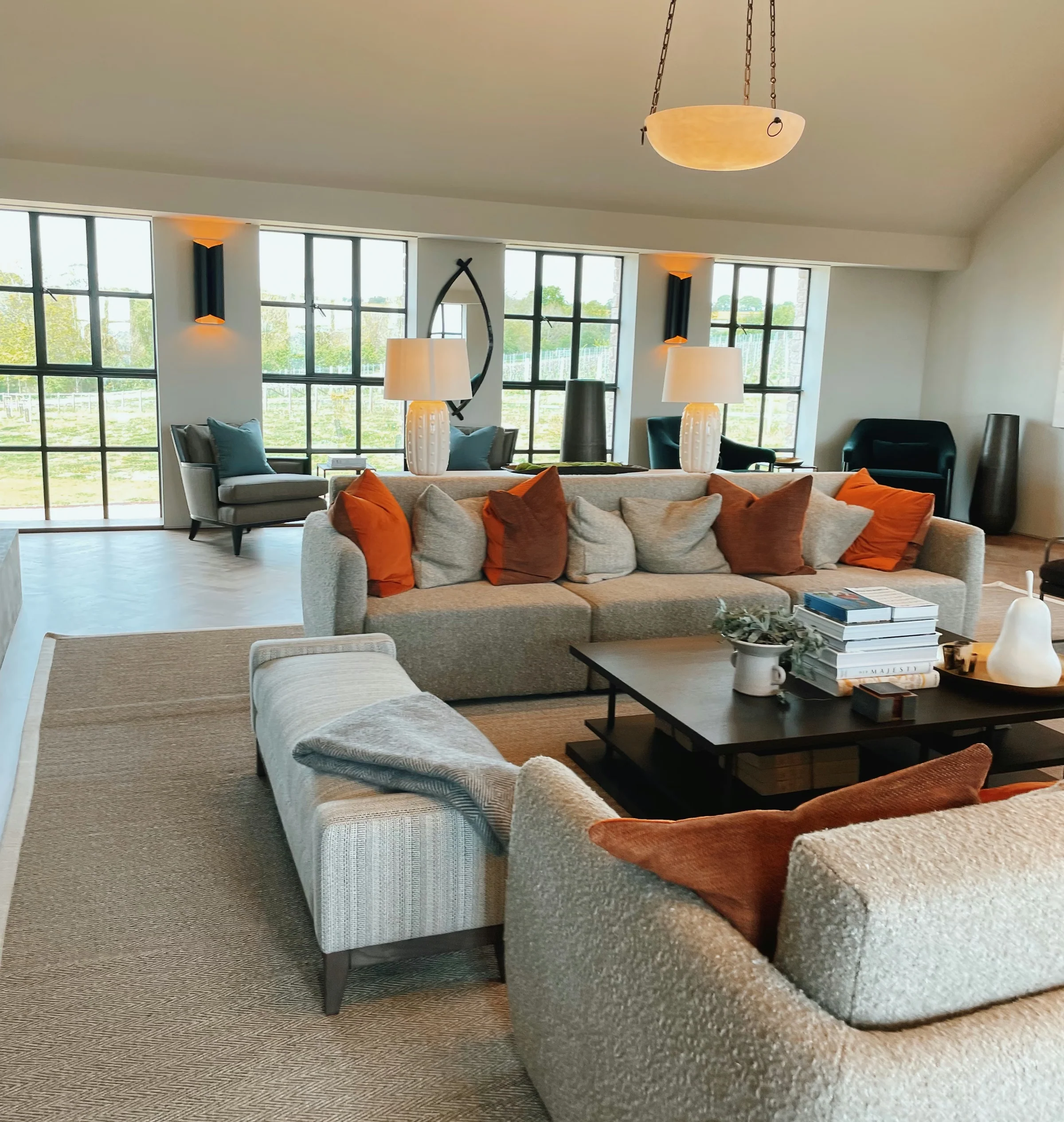 Bright Exton Park tasting room lounge with sofas, armchairs, lamps, coffee table and vineyard views