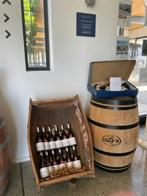 Wine bottles displayed in wooden crate beside barrel stand