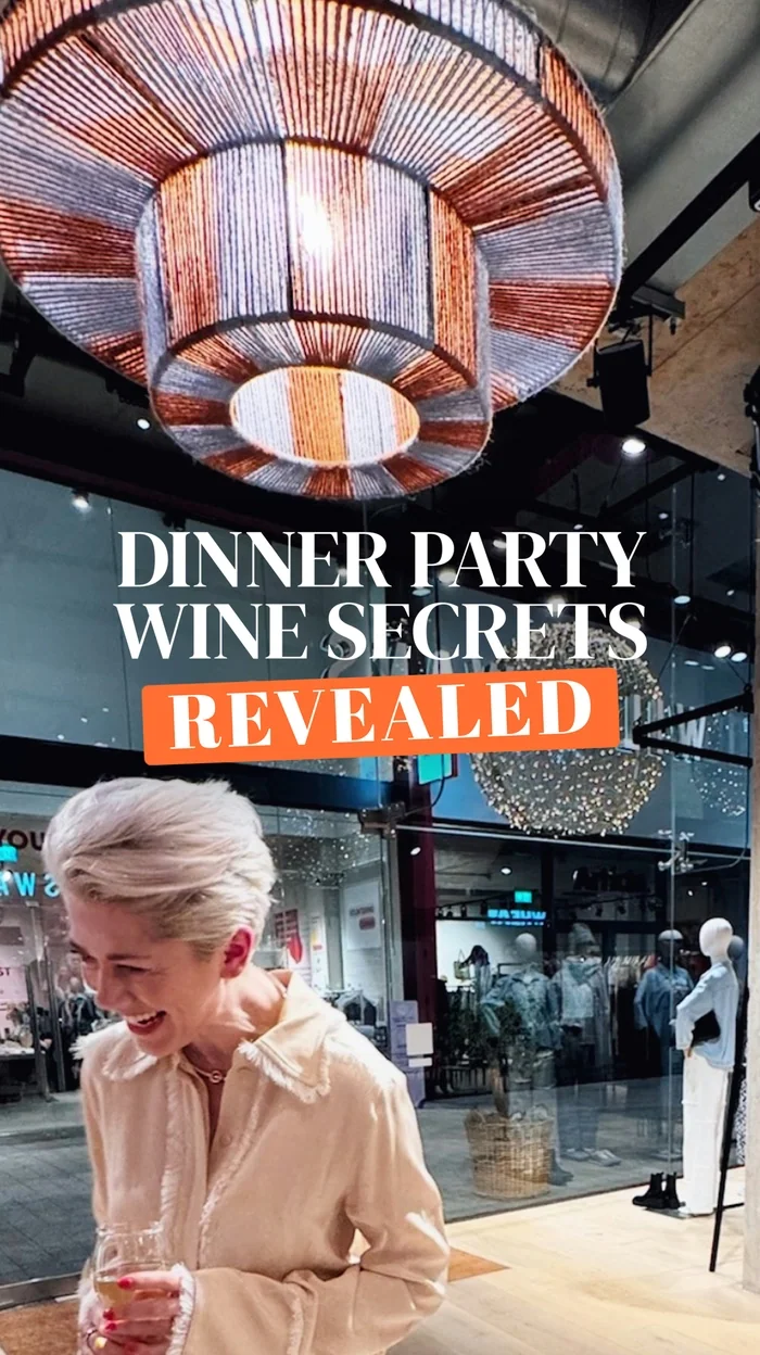 Woman holding wine glass under large chandelier in boutique