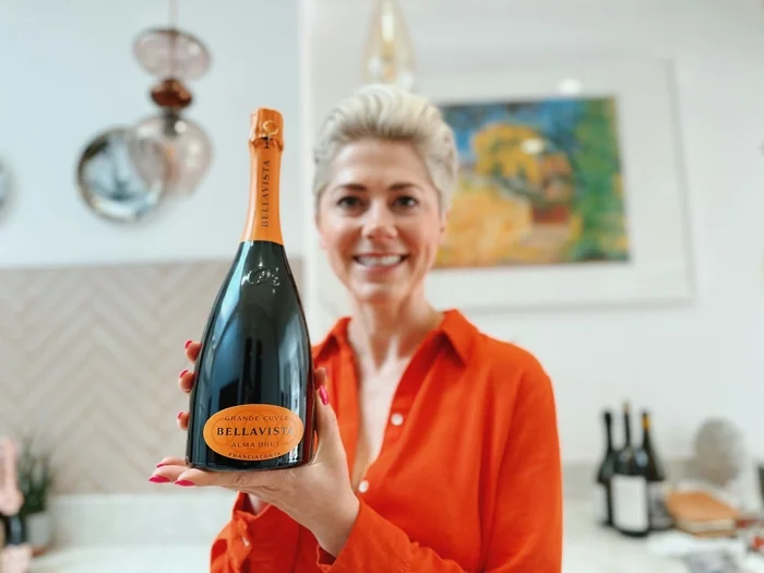 Woman holding Bellavista sparkling wine bottle indoors