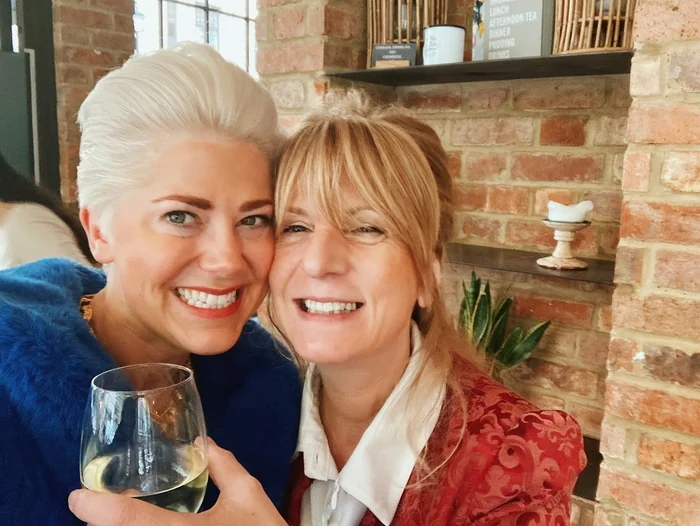Two smiling women holding a glass of white wine in a restaurant