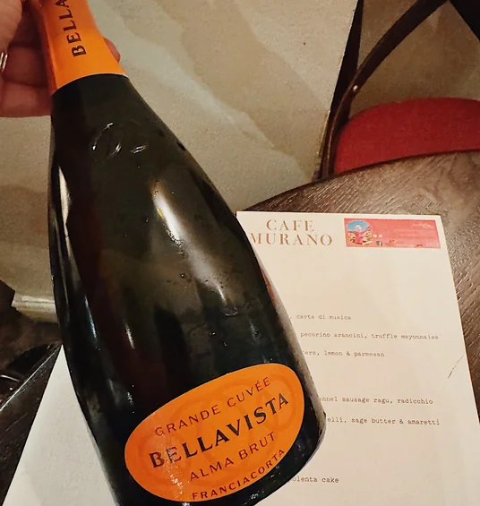 Bellavista Alma Brut bottle beside a Café Murano menu