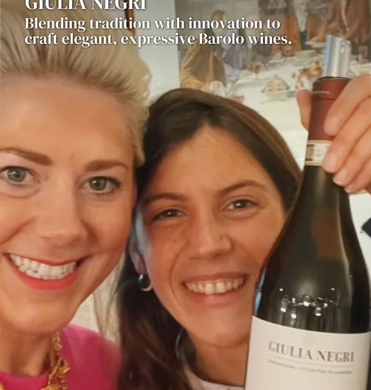Two smiling women pose with a bottle of Giulia Negri Barolo