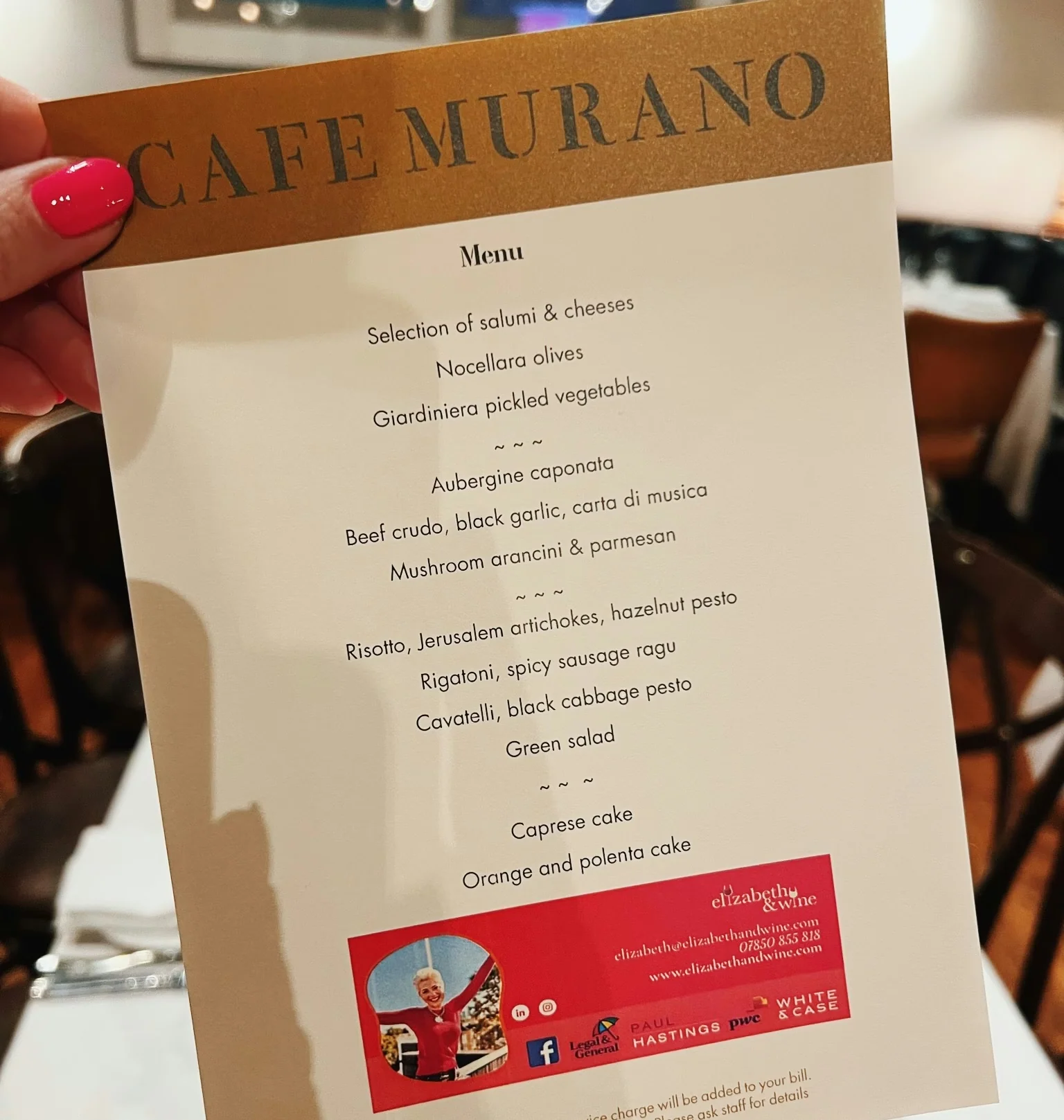 Caffe Murano menu held above a restaurant table, with Elizabeth & Wine branding