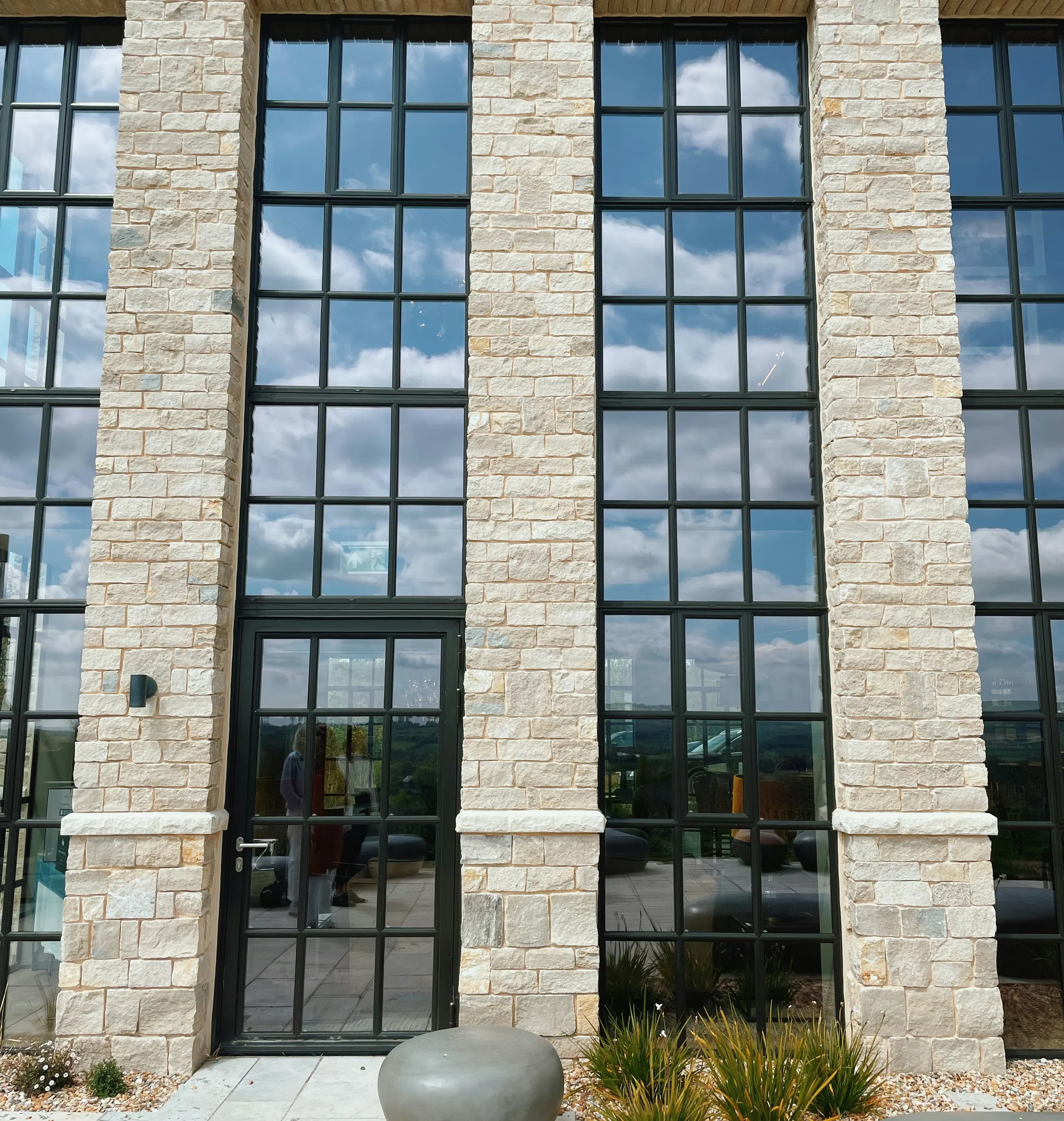 Exton Park tasting room exterior with pale stone walls, tall black-framed windows and landscaped entrance