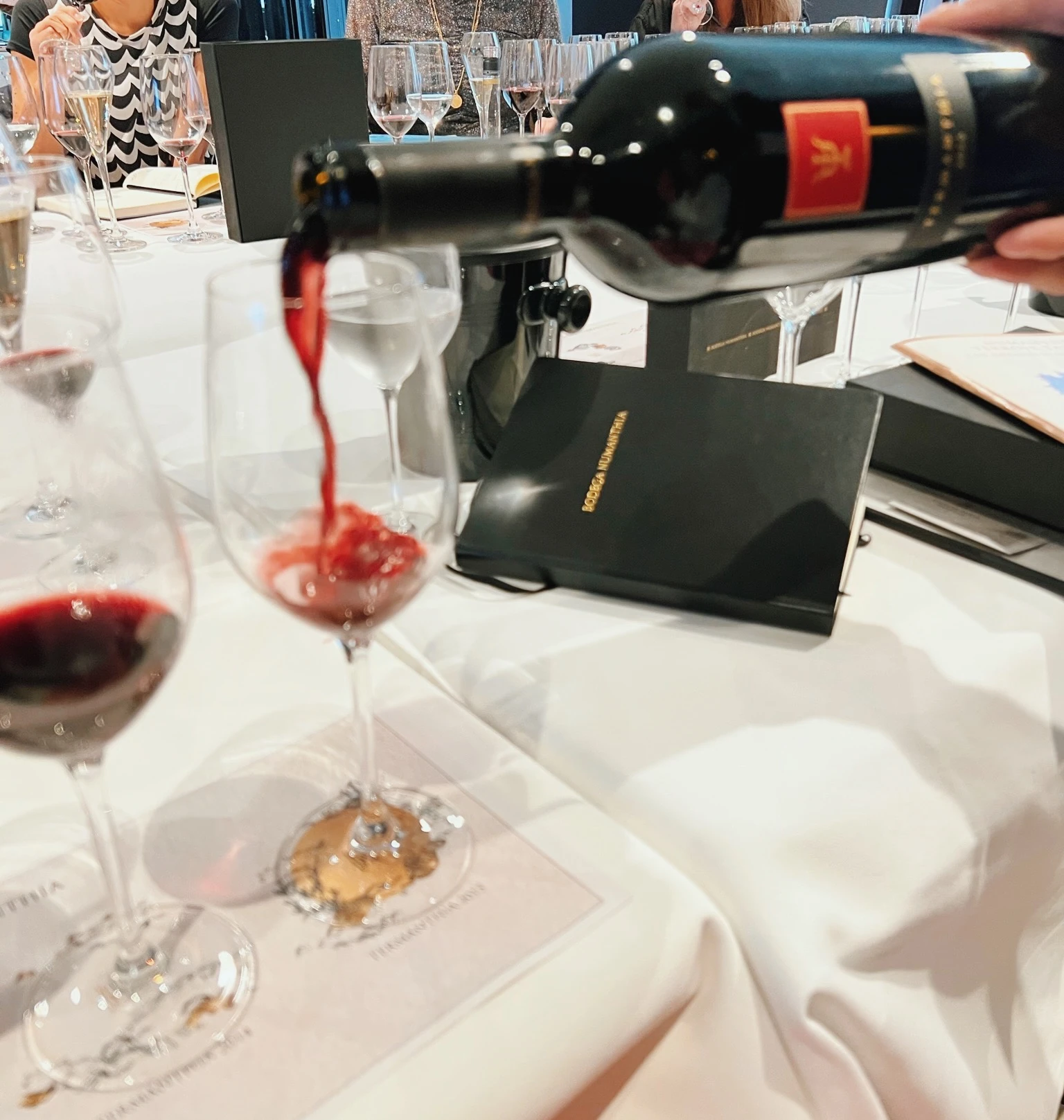 Wine being poured for three guests at a seated tasting