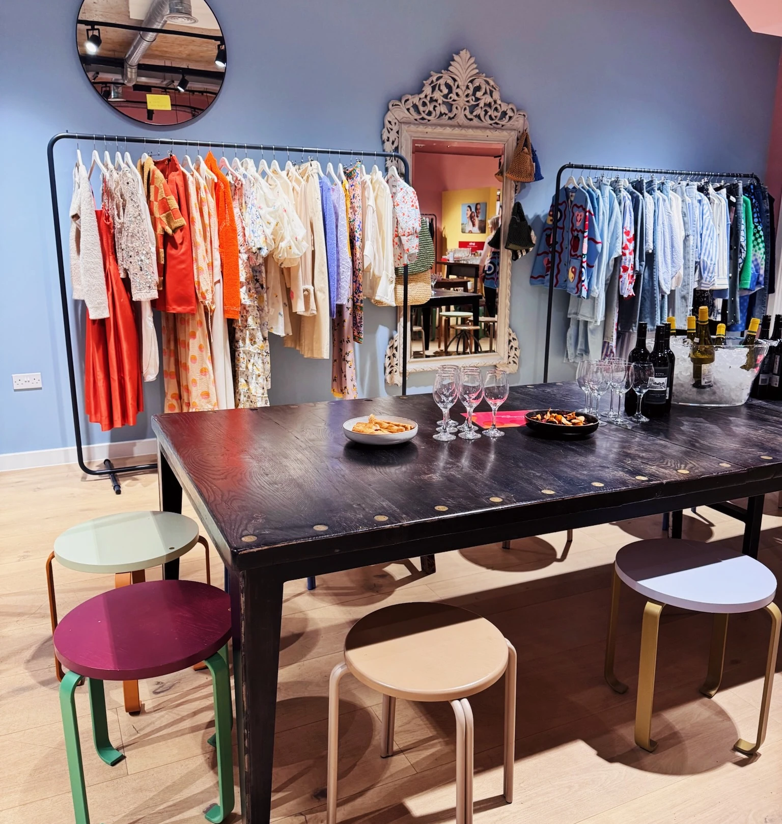 Wine tasting table with glasses and bottles in a colourful fashion boutique