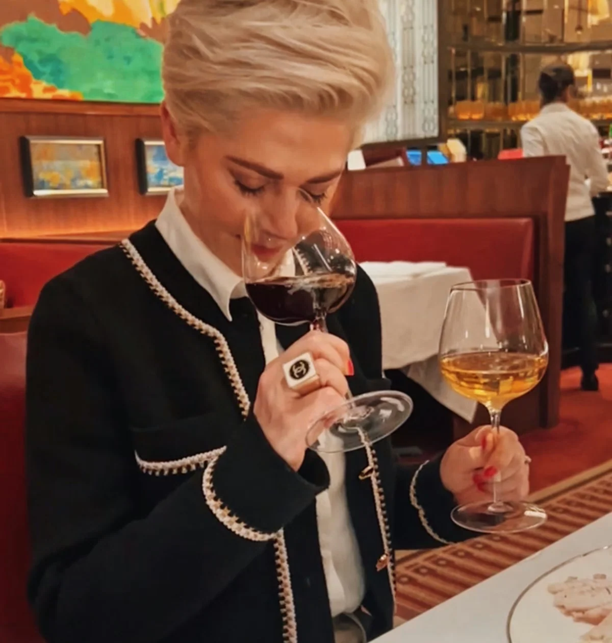 Diner smelling white wine at a restaurant table beside a glass of red wine