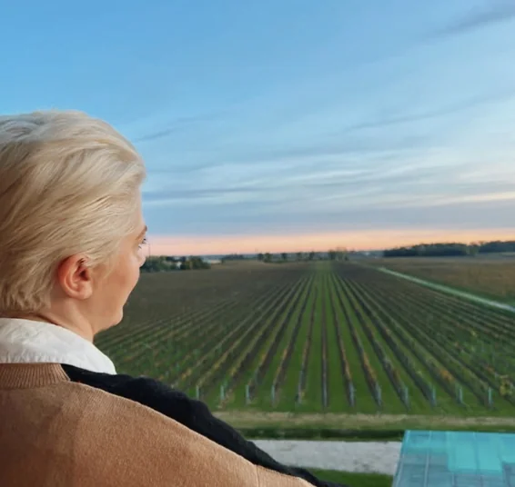 Elizabeth looks over vineyard rows at sunset from a balcony in Italy.