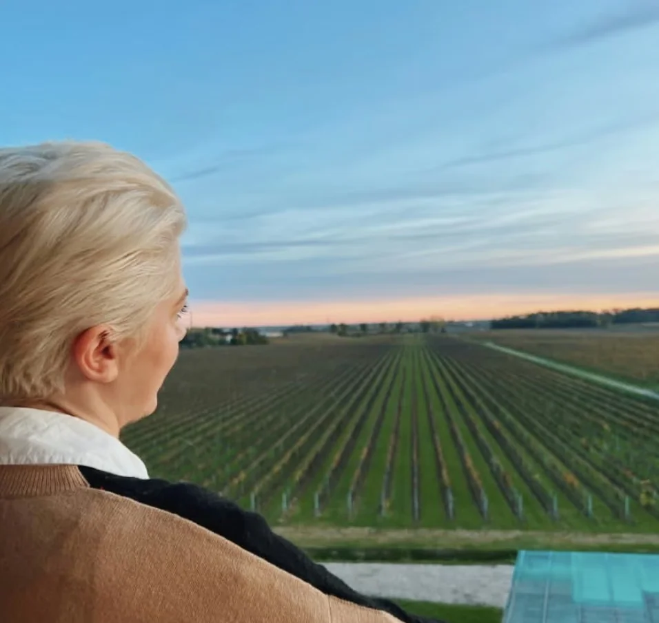 Elizabeth looks over vineyard rows at sunset from a balcony in Italy.